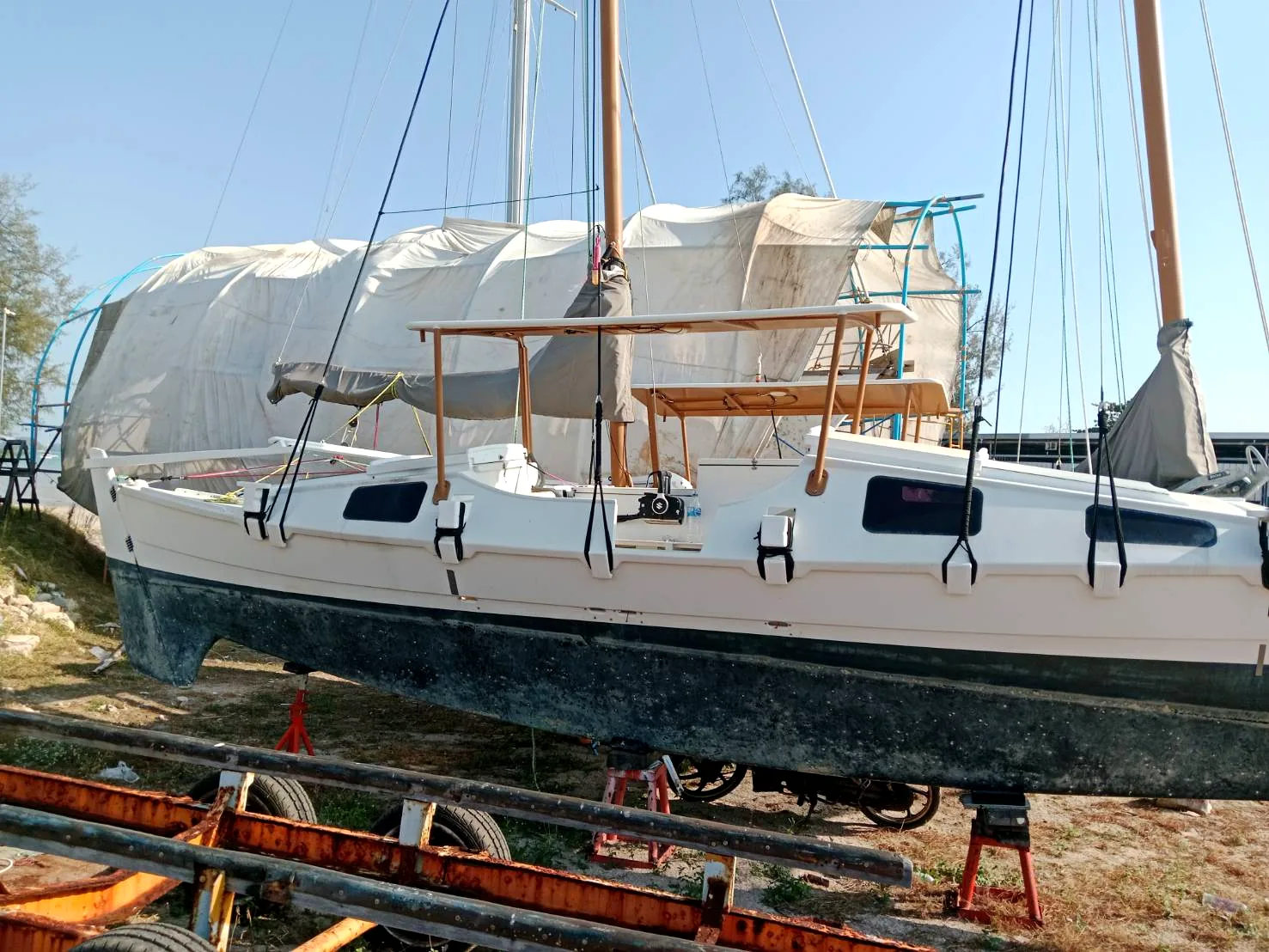 Dragonfly 58 sailing yacht on hardstand at Phuket shipyard — hull repainted, new teak deck installed